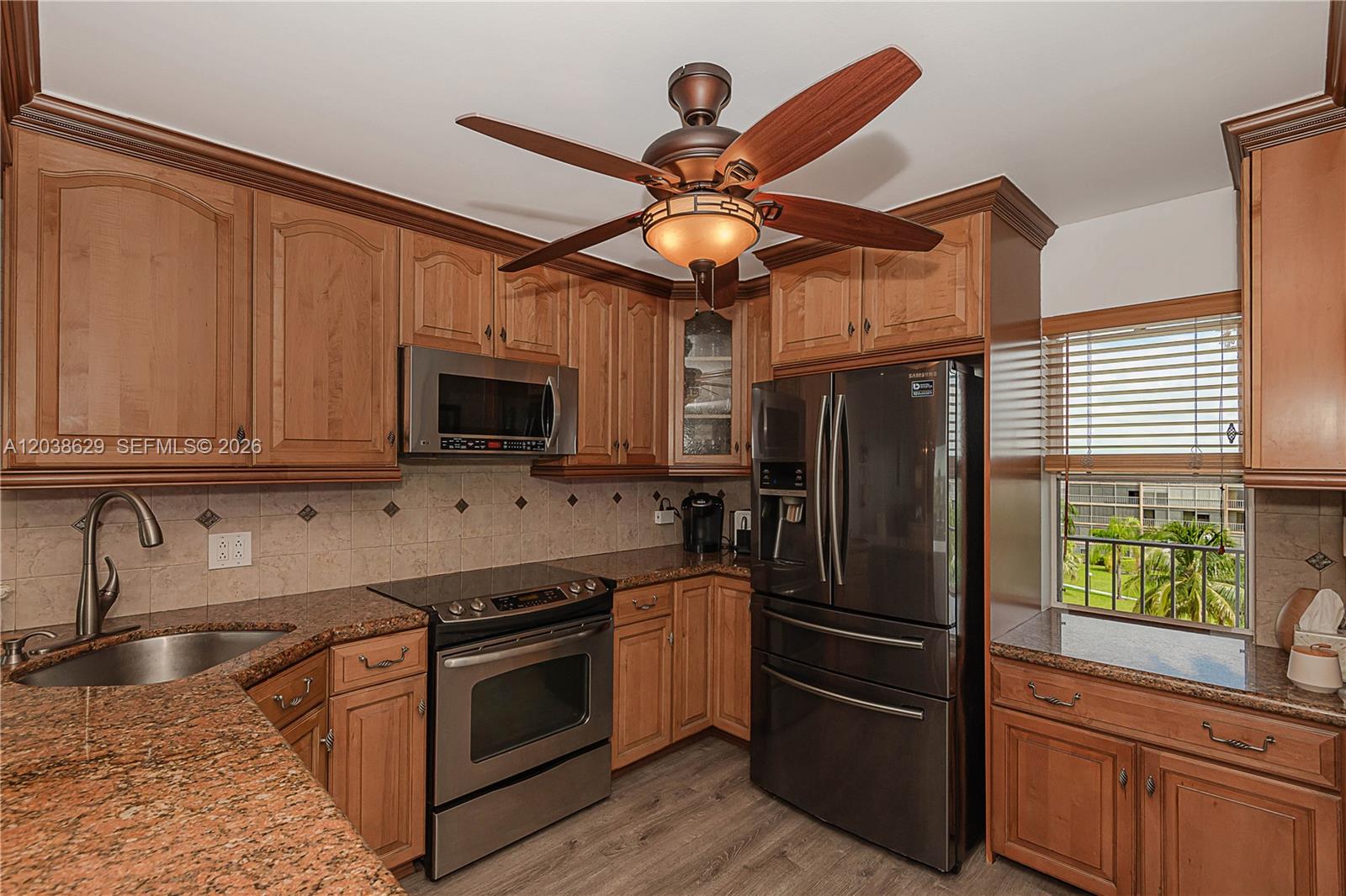 A kitchen features wood cabinets, granite countertops, stainless steel appliances, and a ceiling fan — 4800 Hillcrest Ln # 501, Hollywood FL 33021, HOLLYWOOD, FL