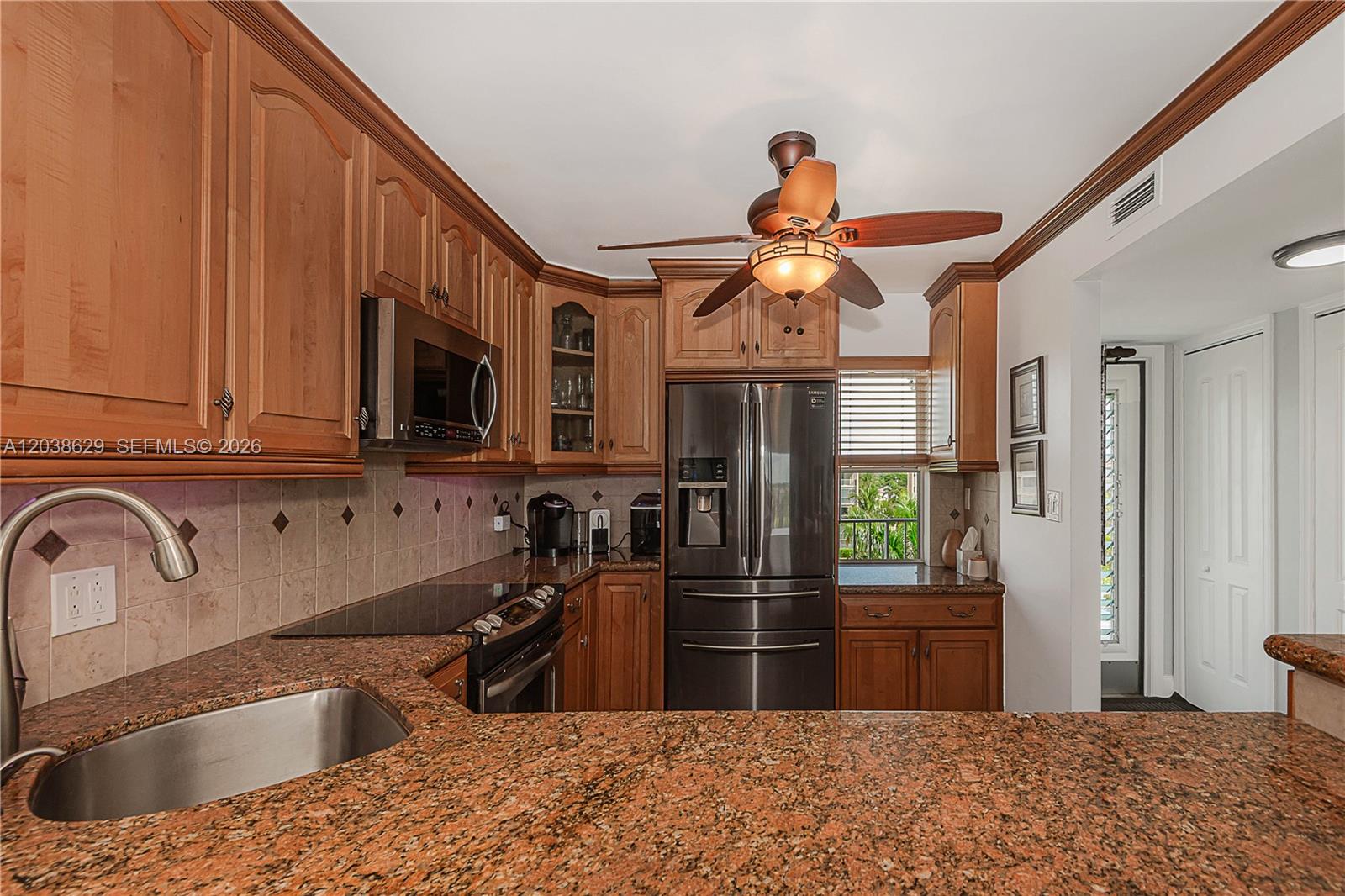 A kitchen features wood cabinets, granite countertops, stainless steel appliances, and a ceiling fan — 4800 Hillcrest Ln # 501, Hollywood FL 33021, HOLLYWOOD, FL