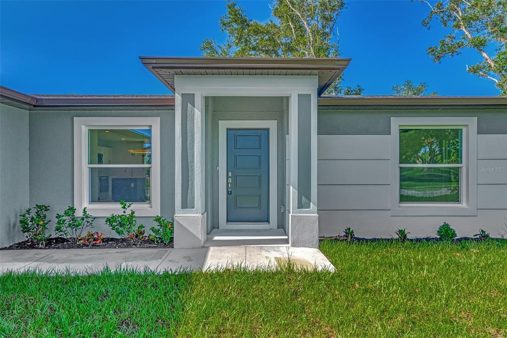 A front exterior view of a house featuring a blue door and gray siding — 3847 E PRICE BOULEVARD, NORTH PORT, FL