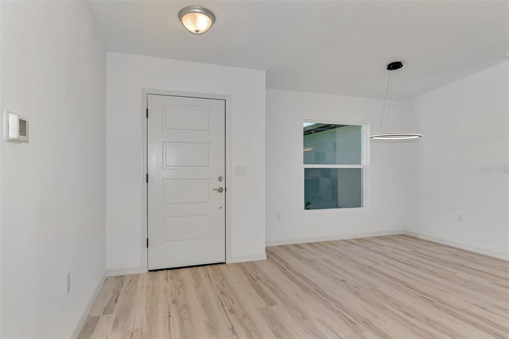 An interior view of a room with white walls, light wood flooring, and a front door — 3847 E PRICE BOULEVARD, NORTH PORT, FL