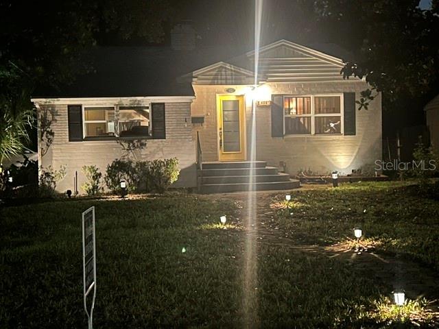 A single-story house with a yellow front door and exterior landscape lighting at night — 428 ALTALOMA AVENUE, ORLANDO, FL