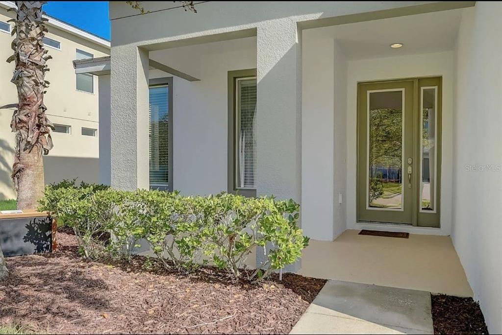 A front entryway features a light-colored stucco exterior, a green door, and a small porch — 4511 MONADO DRIVE, KISSIMMEE, FL