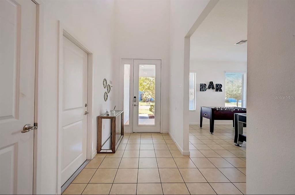A bright entryway with tile flooring leads to a room containing a foosball table — 4511 MONADO DRIVE, KISSIMMEE, FL