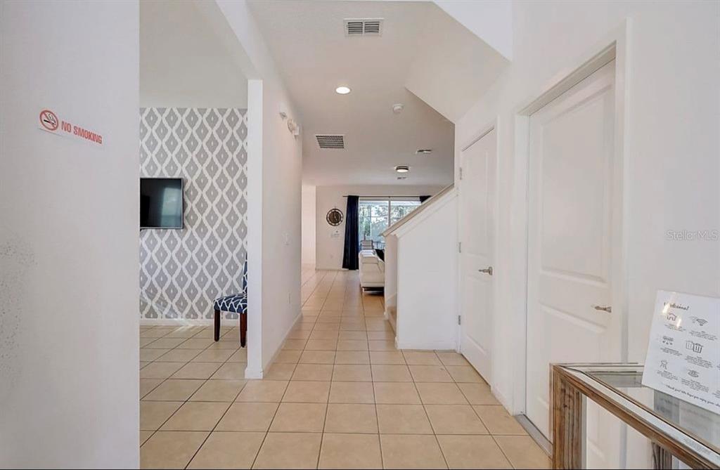 A tiled hallway leads past a patterned accent wall toward a living area — 4511 MONADO DRIVE, KISSIMMEE, FL