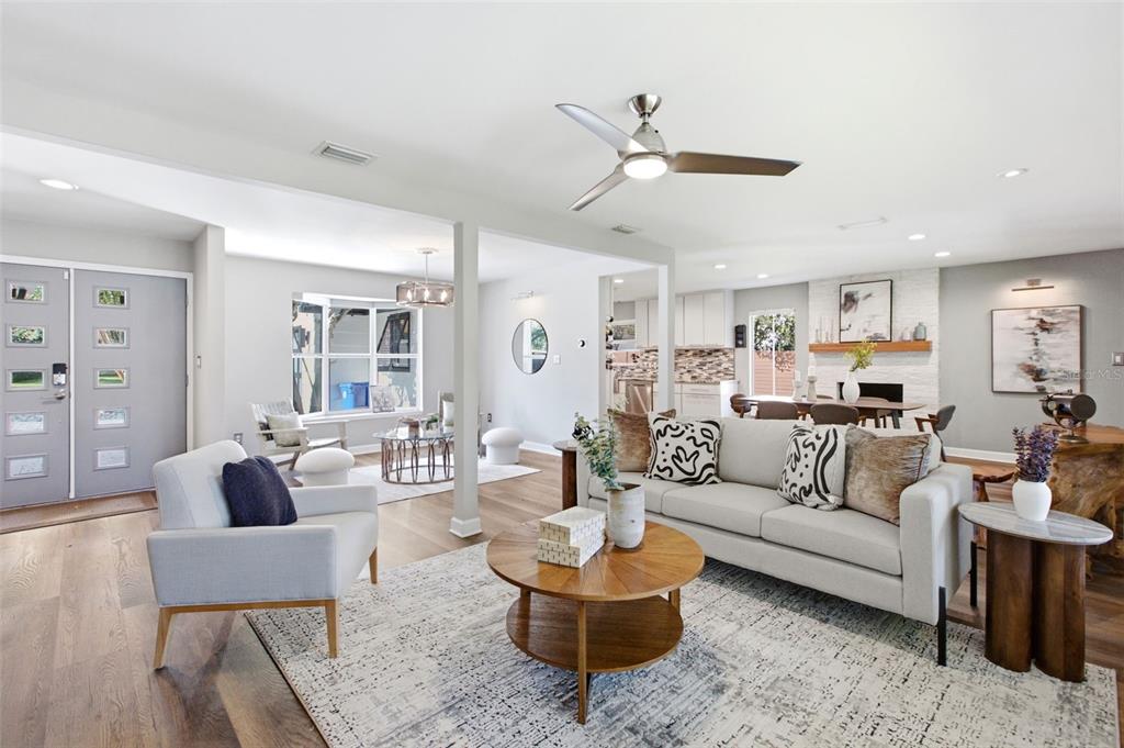 A bright, open-concept living room features light wood floors, a modern ceiling fan, and furniture — 465 MANDALAY ROAD, ORLANDO, FL
