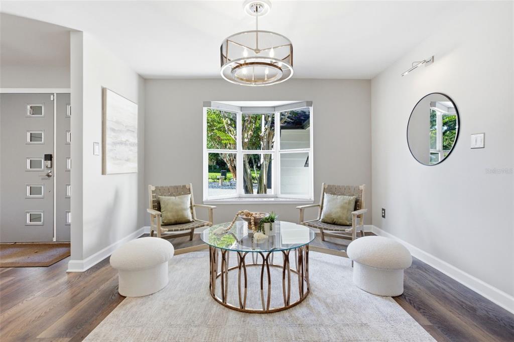 A bright sitting area features two wooden chairs, a glass coffee table, and a bay window — 465 MANDALAY ROAD, ORLANDO, FL