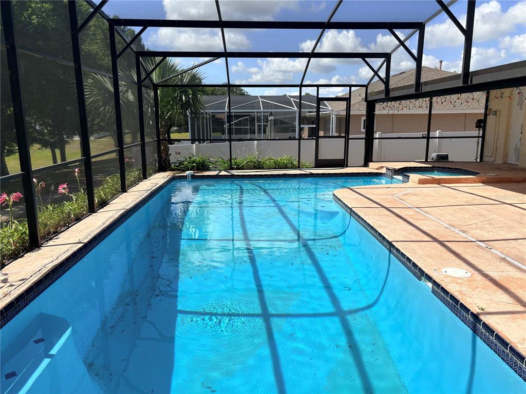 A screened-in swimming pool and spa area with a tiled deck and surrounding white fence — 1105 INDIAN RIDGE TRAIL E, KISSIMMEE, FL