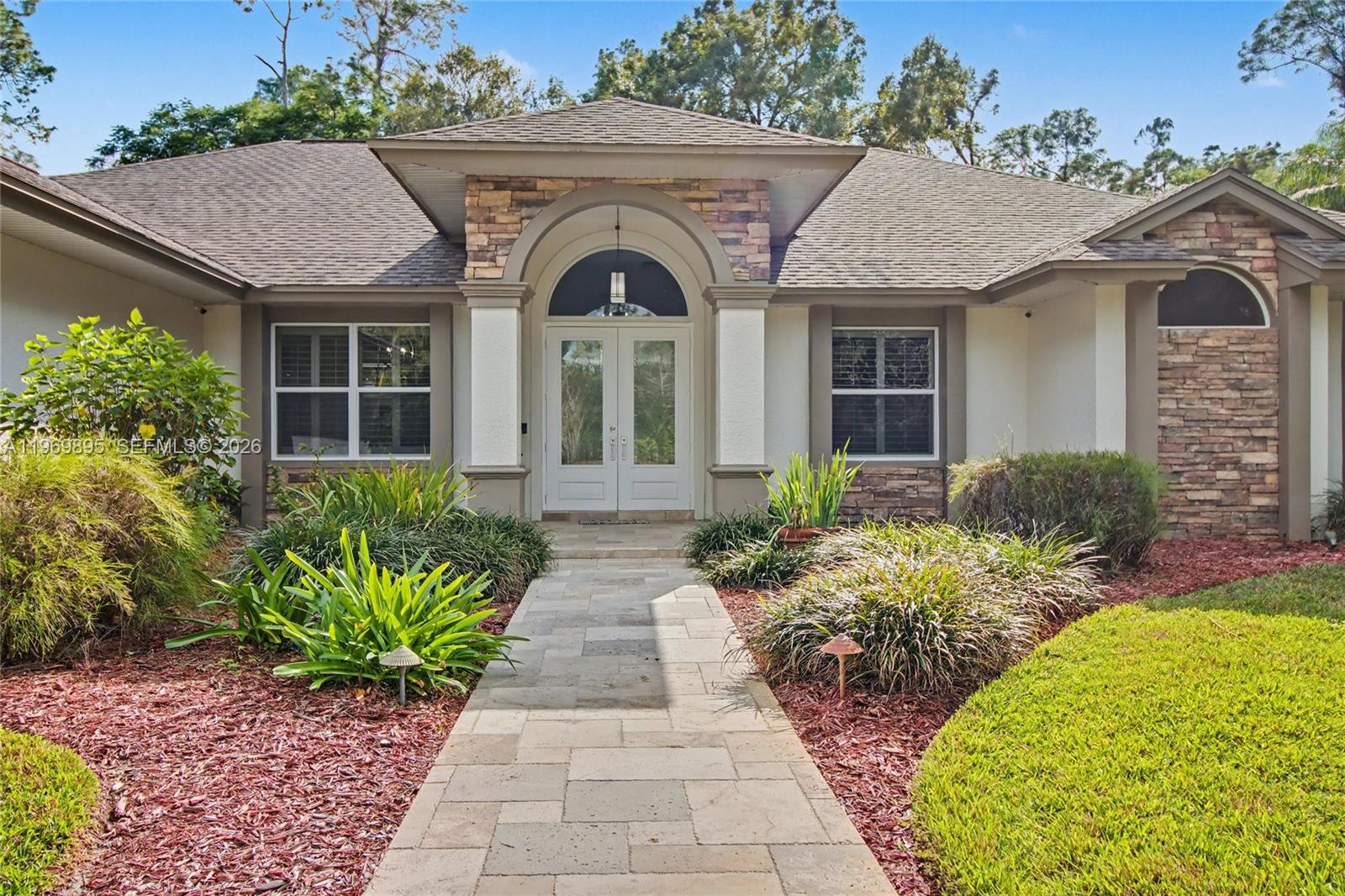 The exterior of a single-story house features a stone-accented entryway and a stone-paved walkway — 5186 Tallowood Way, Naples FL 34116, NAPLES, FL