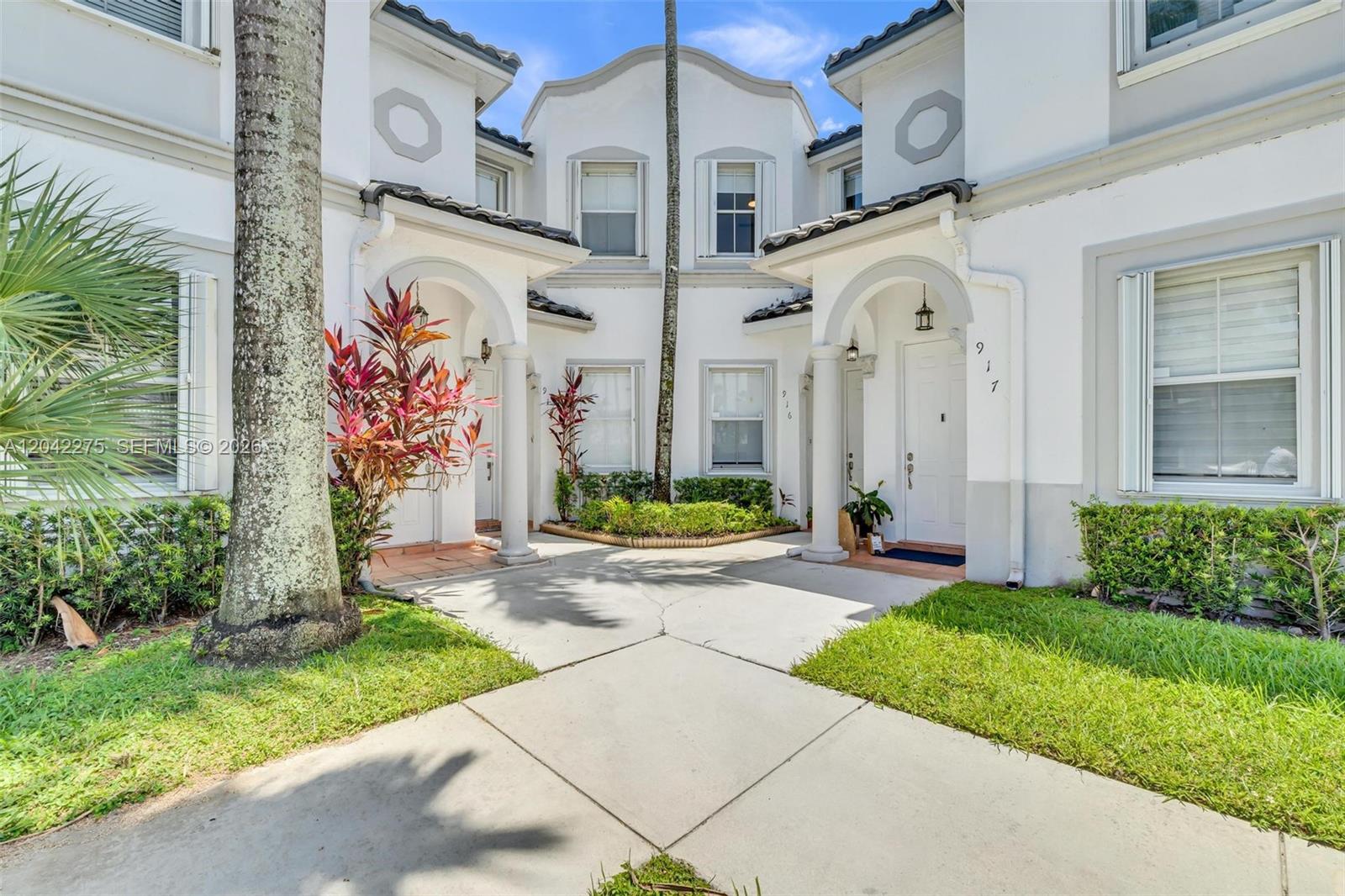 The exterior of a two-story white townhouse with a concrete walkway and arched entryways — 5570 NW 107th Ave # 916, Doral FL 33178, DORAL, FL