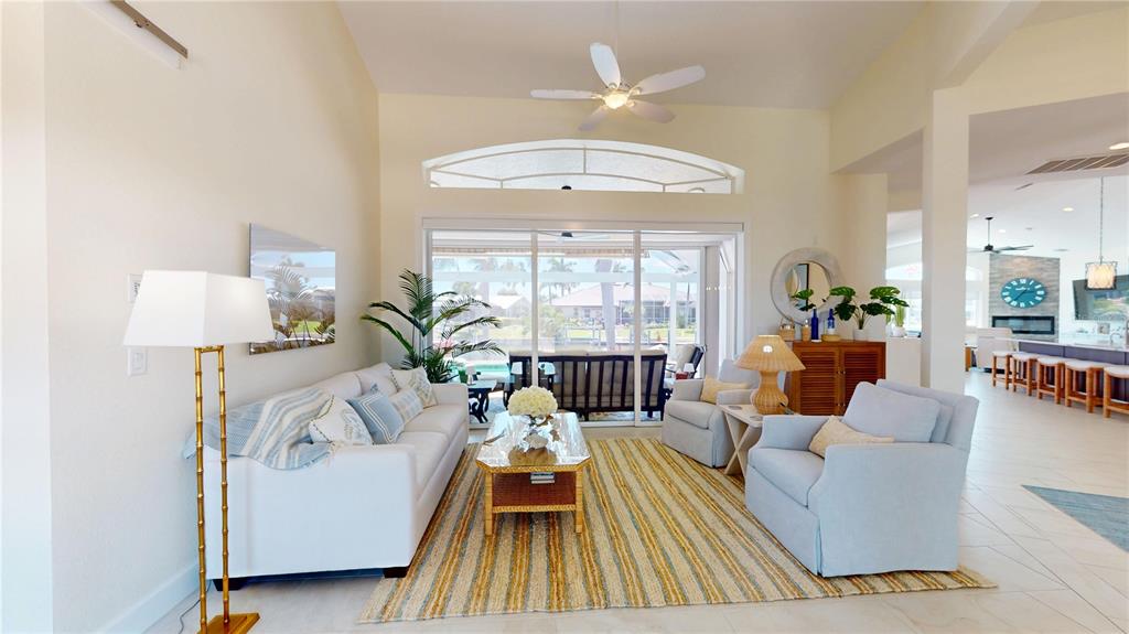 A bright living room features a white sofa, two armchairs, and a striped area rug — 136 GREAT ISAAC COURT, PUNTA GORDA, FL