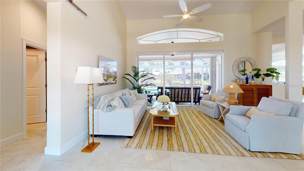 A bright living room features a white sofa, two armchairs, and a sliding glass door — 136 GREAT ISAAC COURT, PUNTA GORDA, FL