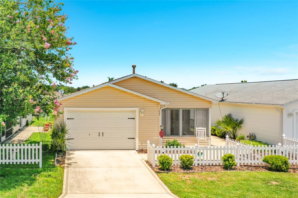 A single-story house with light yellow siding, a white garage door, and a white picket fence — 3598 CAMBRIA CIRCLE, THE VILLAGES, FL
