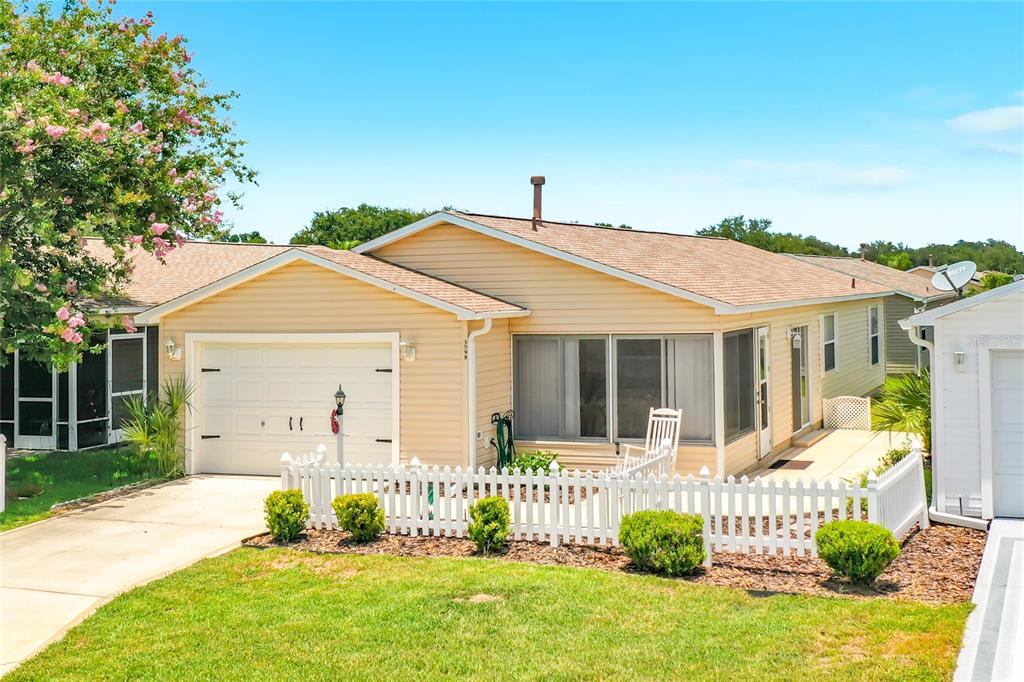 A single-story house with light yellow siding, a white garage door, and a white picket fence — 3598 CAMBRIA CIRCLE, THE VILLAGES, FL