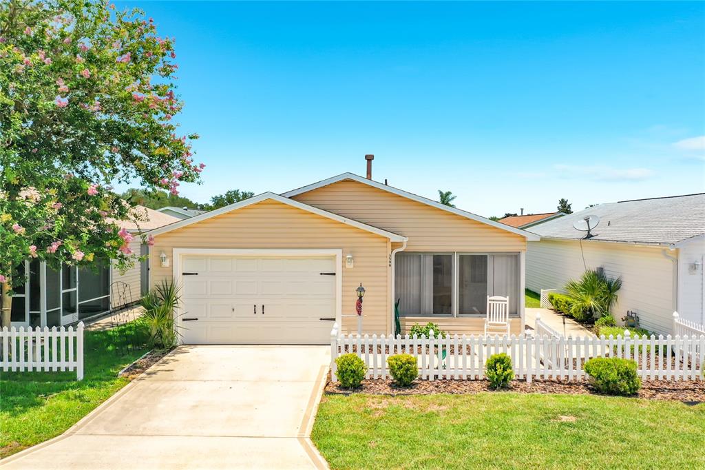 A single-story house with tan siding, a white garage door, and a white picket fence — 3598 CAMBRIA CIRCLE, THE VILLAGES, FL