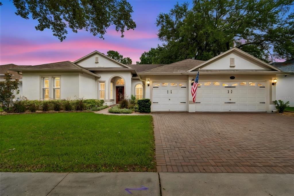 A single-story house with a white stucco exterior, a brick driveway, and a two-car garage — 3825 MISTY LANDING DRIVE, VALRICO, FL