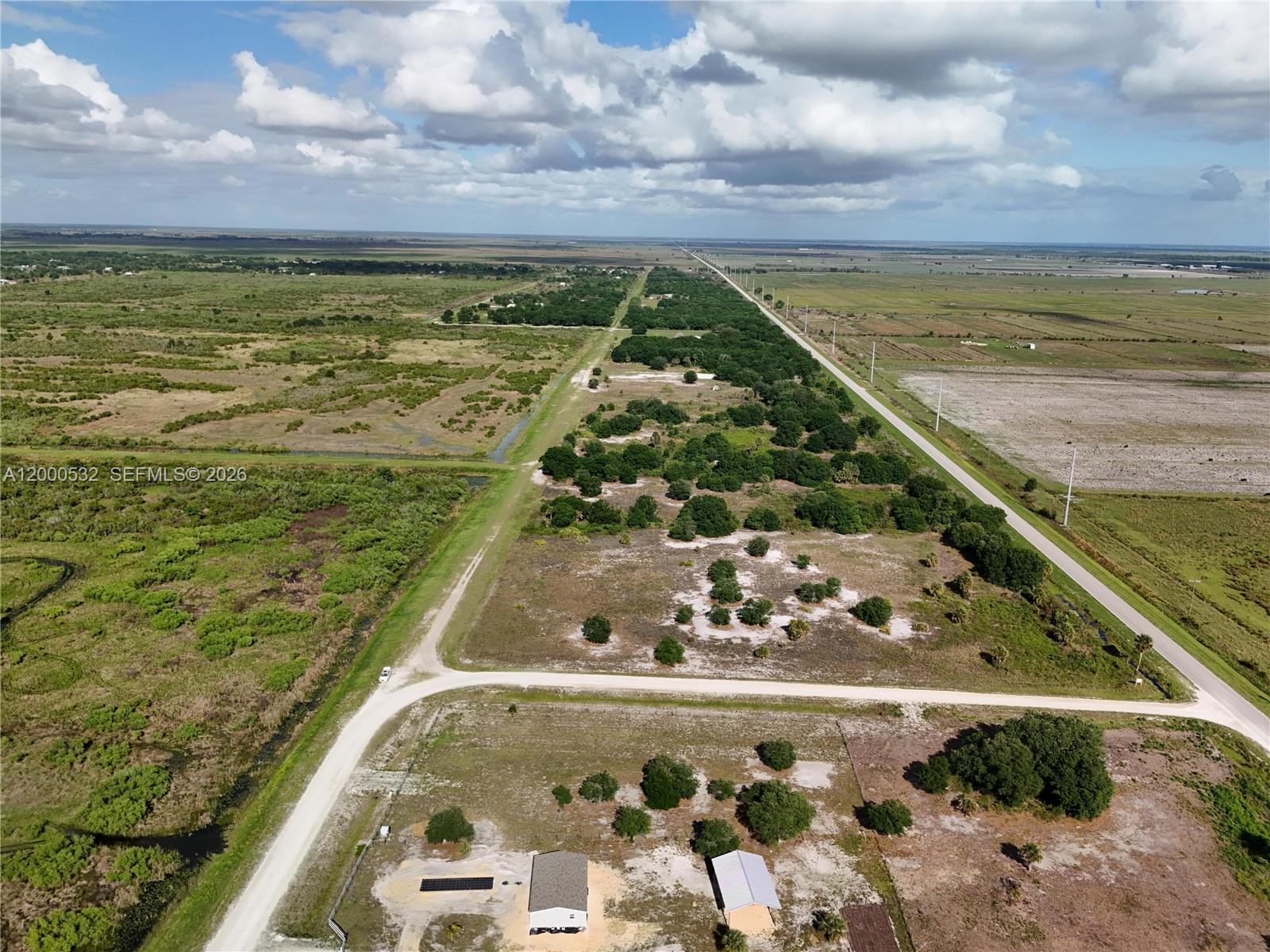 An aerial view shows a rural property with a house, outbuilding, and surrounding undeveloped land — 16734 NW 242ND, Okeechobee FL 34972, OKEECHOBEE, FL