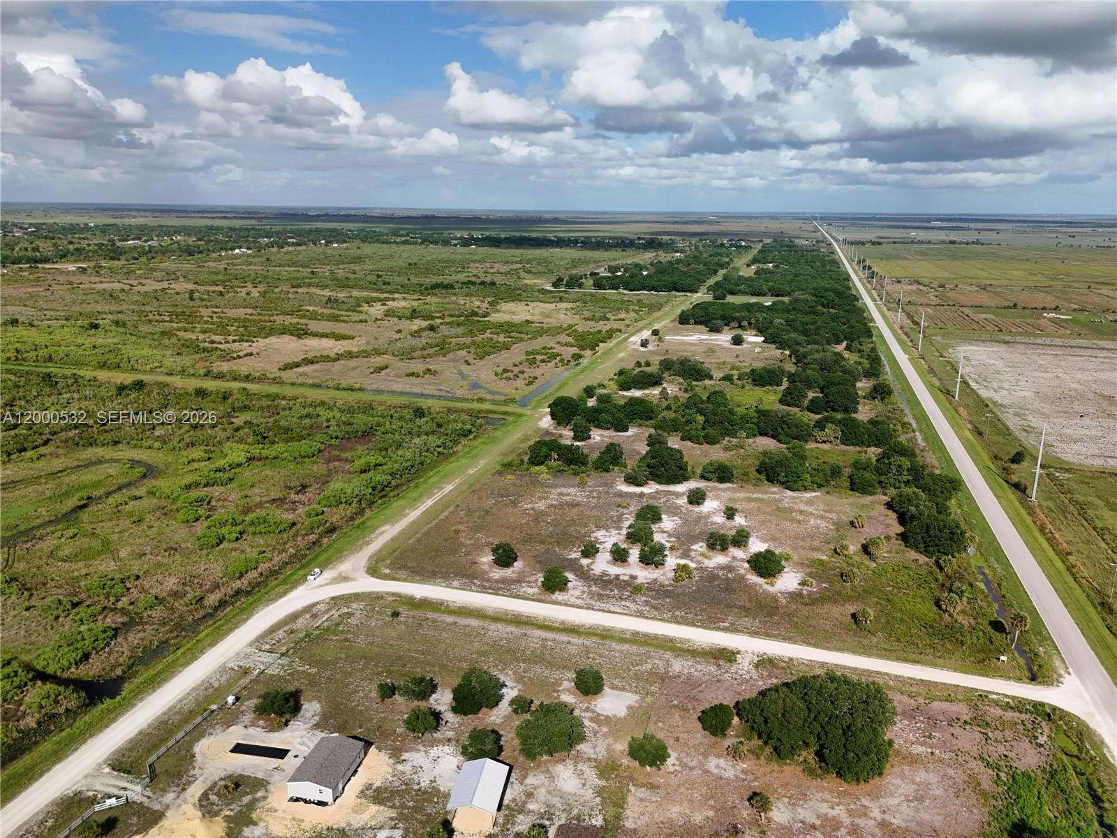 An aerial view shows a rural property with a house, outbuilding, and surrounding undeveloped land — 16734 NW 242ND, Okeechobee FL 34972, OKEECHOBEE, FL