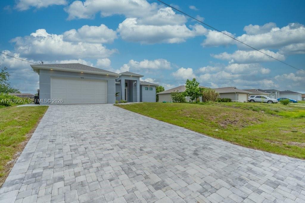 A single-story house with a gray exterior, a two-car garage, and a paved driveway — 5054 Benton St, Lehigh Acres FL 33971, LEHIGH ACRES, FL