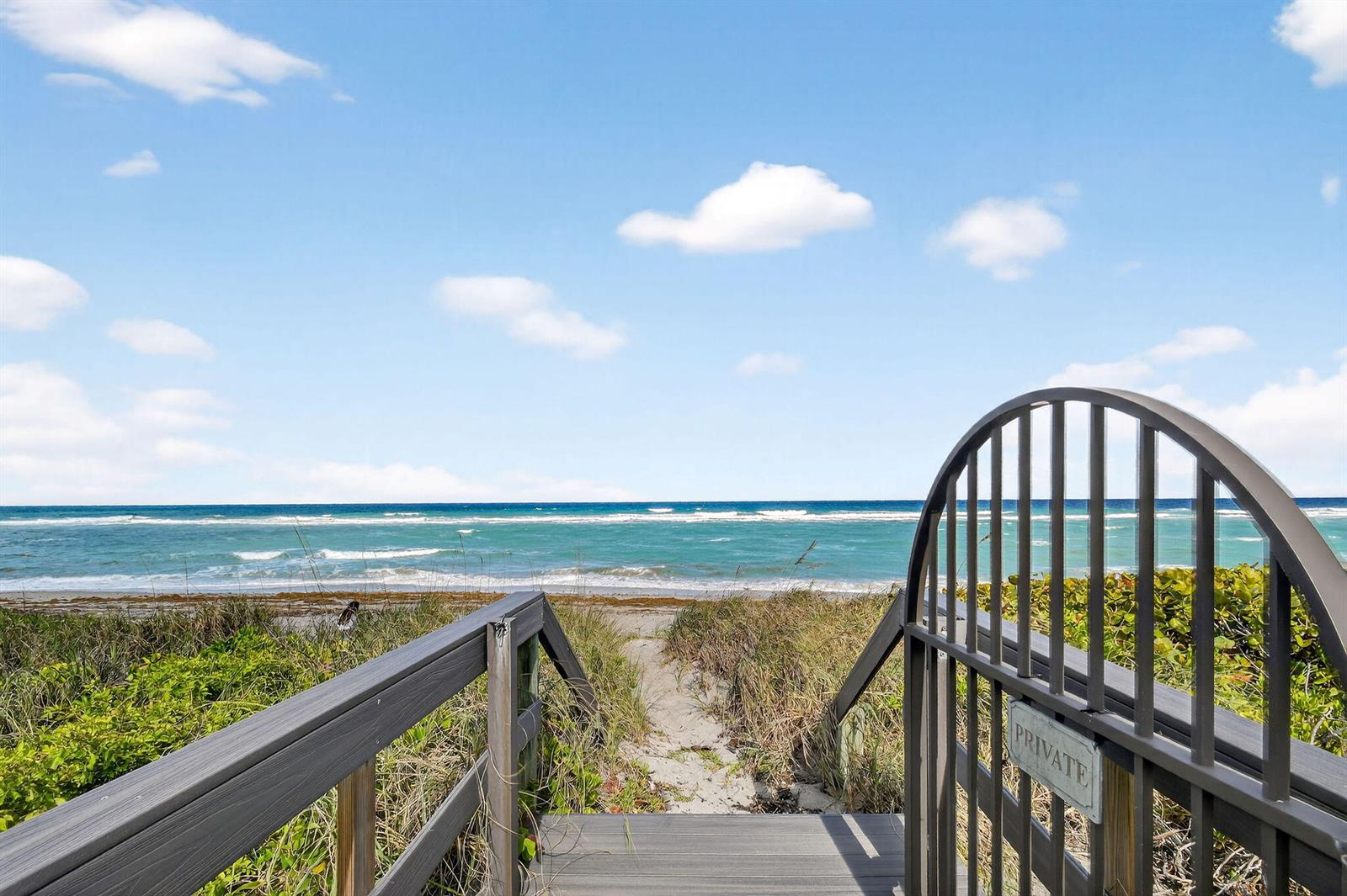 A wooden staircase leads through a private gate toward a sandy beach and the ocean — 302 Alicante Drive, Juno Beach FL 33408, JUNO BEACH, FL