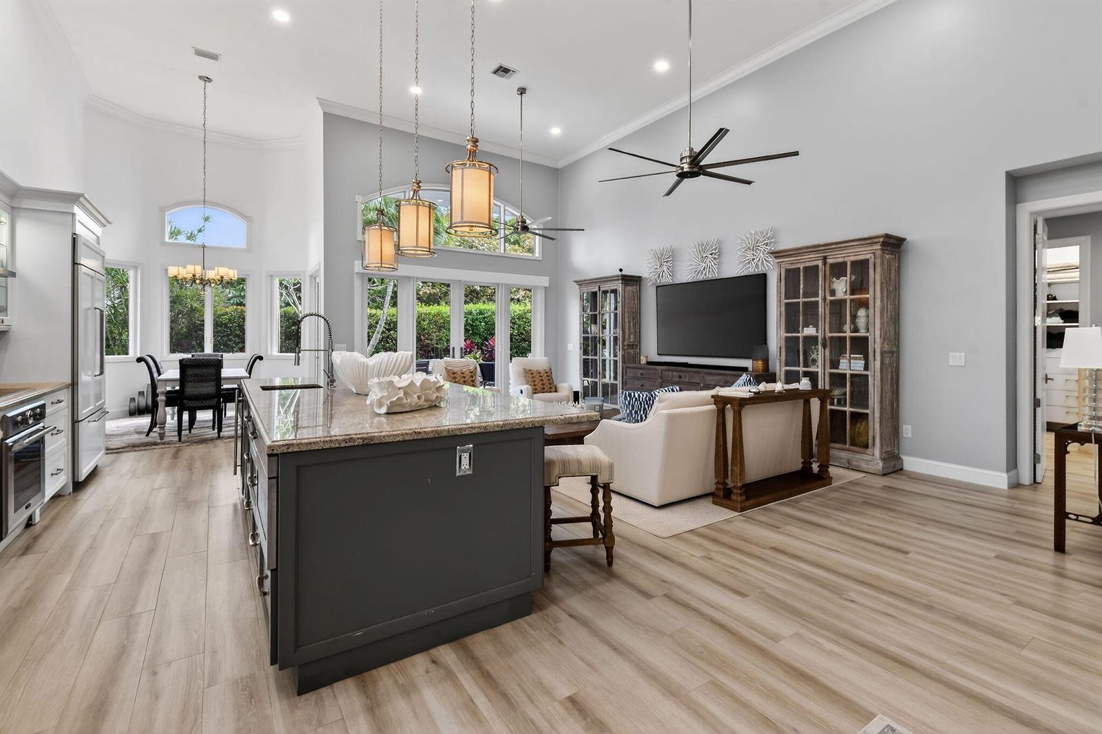 A spacious open-concept kitchen and living area with a large island, light wood flooring, and cabinetry — 302 Alicante Drive, Juno Beach FL 33408, JUNO BEACH, FL