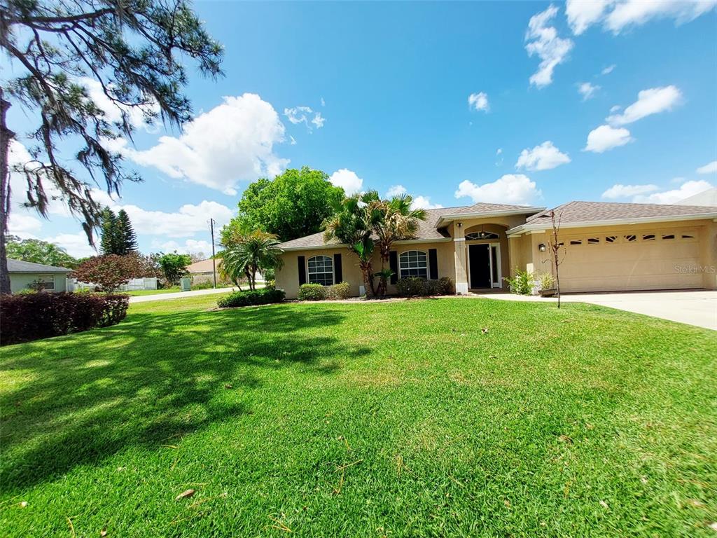 A single-story house with a tan exterior, a two-car garage, and a large front lawn — 4031 SANTA BARBARA DRIVE, SEBRING, FL