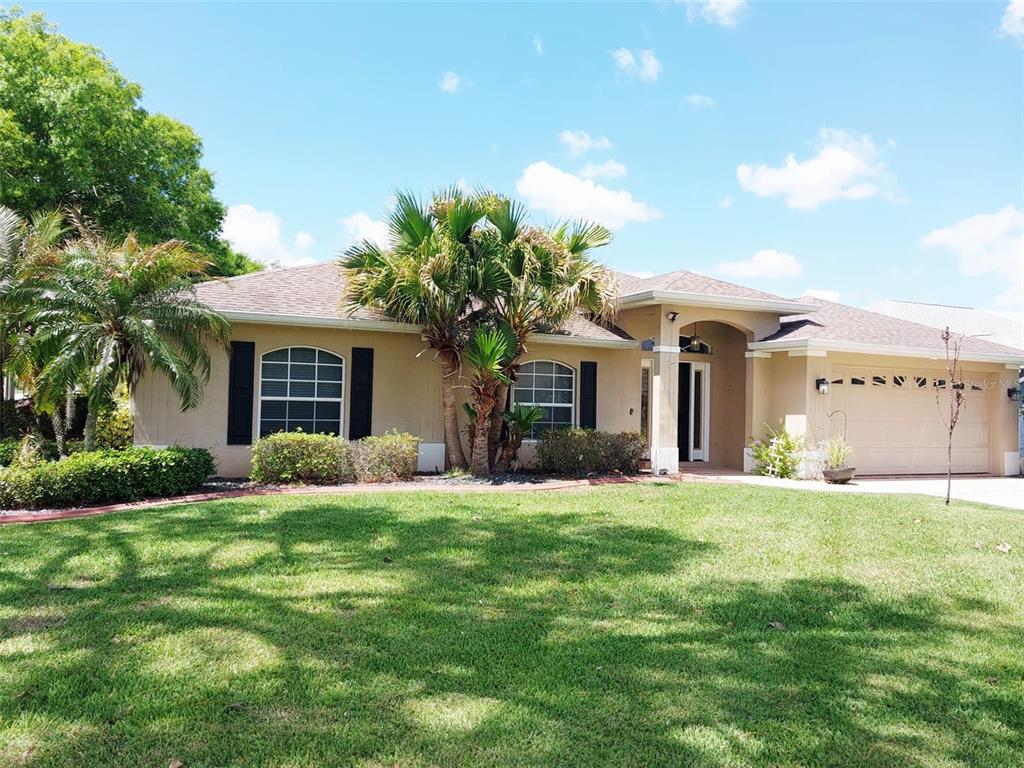 A single-story house with a tan stucco exterior, a two-car garage, and a palm tree — 4031 SANTA BARBARA DRIVE, SEBRING, FL