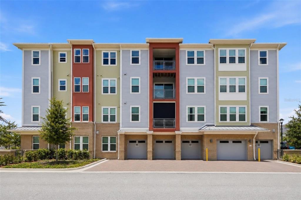 A four-story apartment building with a mix of light blue, green, and red exterior siding — 7521 LAUREATE BOULEVARD UNIT 5403, ORLANDO, FL