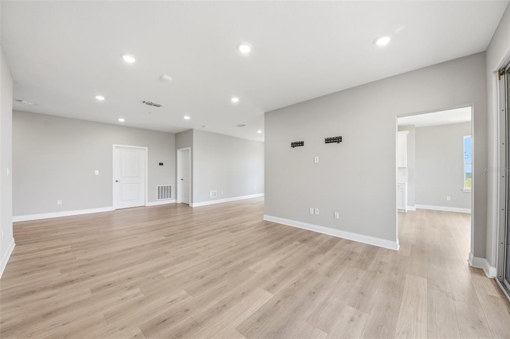 An empty living room features light wood-look flooring, gray walls, and recessed ceiling lighting — 7521 LAUREATE BOULEVARD UNIT 5403, ORLANDO, FL