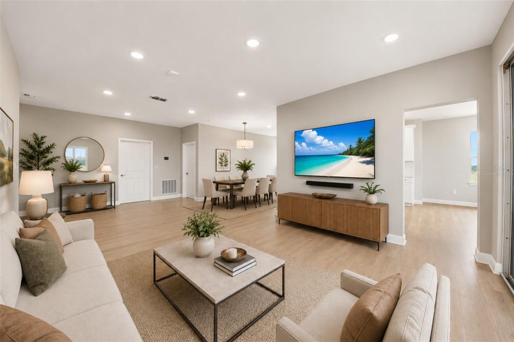 A living room with light wood floors, a wall-mounted television, and an adjacent dining area — 7521 LAUREATE BOULEVARD UNIT 5403, ORLANDO, FL