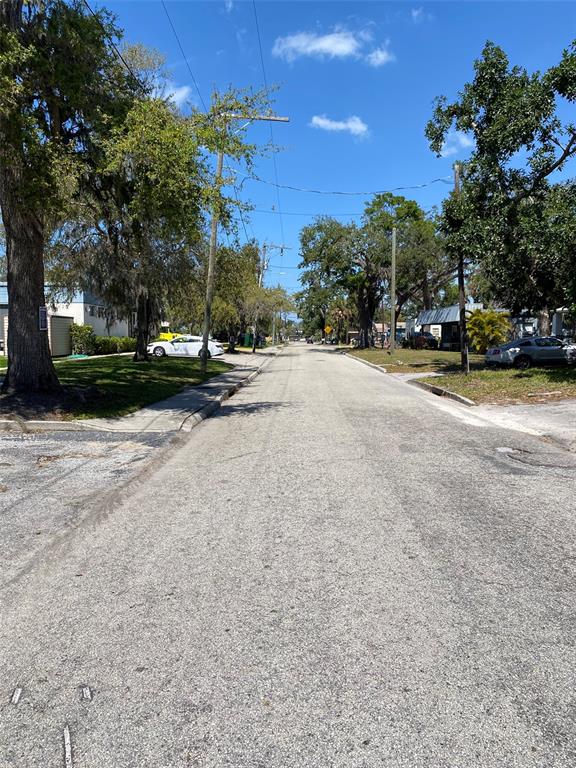 A paved residential street lined with mature trees and utility poles under a clear sky — 518 7TH AVENUE W, PALMETTO, FL