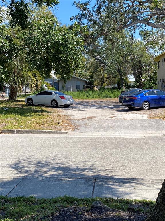 A gravel parking area sits between two cars with trees and a small house behind — 518 7TH AVENUE W, PALMETTO, FL