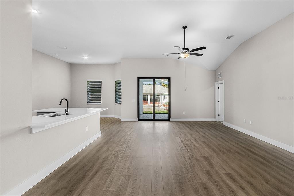 An open-concept living room features light gray walls, wood-look flooring, and a kitchen island — 4570 GILLOT BOULEVARD, PORT CHARLOTTE, FL