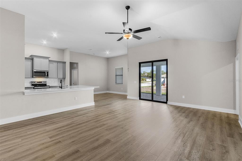 An open-concept living area features light wood-look flooring, a ceiling fan, and a kitchen island — 4570 GILLOT BOULEVARD, PORT CHARLOTTE, FL