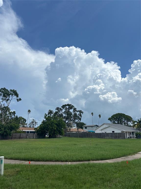 A vacant, grassy residential lot is bordered by a sidewalk, wooden fences, and nearby houses — BAYOU GRANDE BOULEVARD NE, ST PETERSBURG, FL