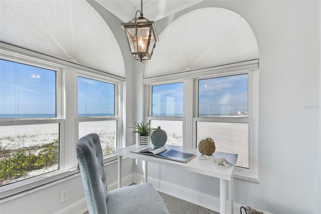 A desk with a chair sits in a corner room overlooking a sandy beach — 4950 GULF BOULEVARD UNIT 206, ST PETE BEACH, FL