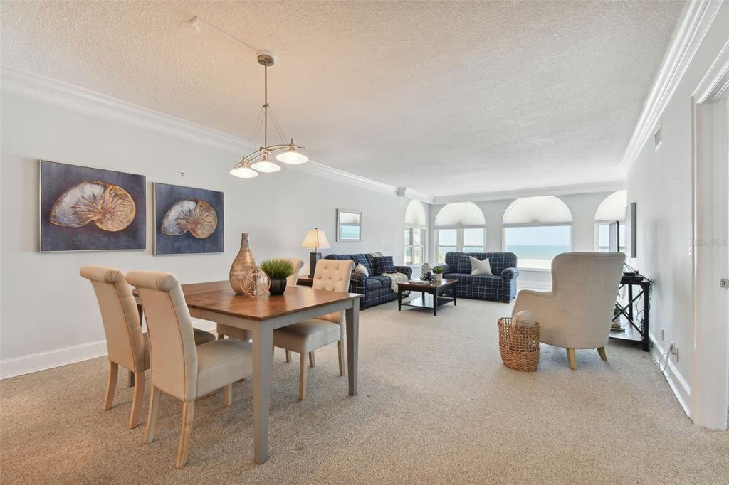 A dining area and living room with beige carpet, blue plaid furniture, and ocean views — 4950 GULF BOULEVARD UNIT 206, ST PETE BEACH, FL