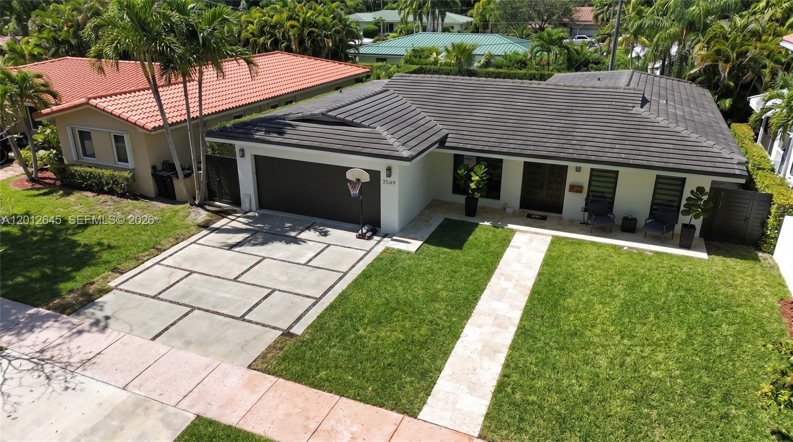 An aerial view shows a single-story house with a dark tiled roof and driveway — 1549 Zuleta Ave, Coral Gables FL 33146, CORAL GABLES, FL