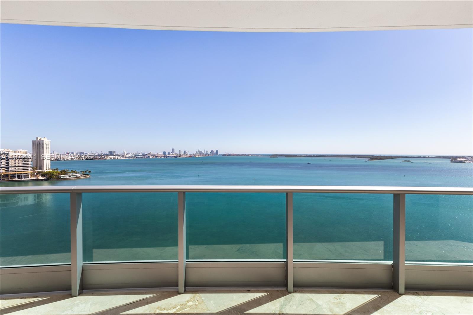 A balcony with a glass railing overlooks a wide bay and a distant city skyline — 1331 Brickell Bay Dr # 1901, Miami FL 33131, MIAMI, FL