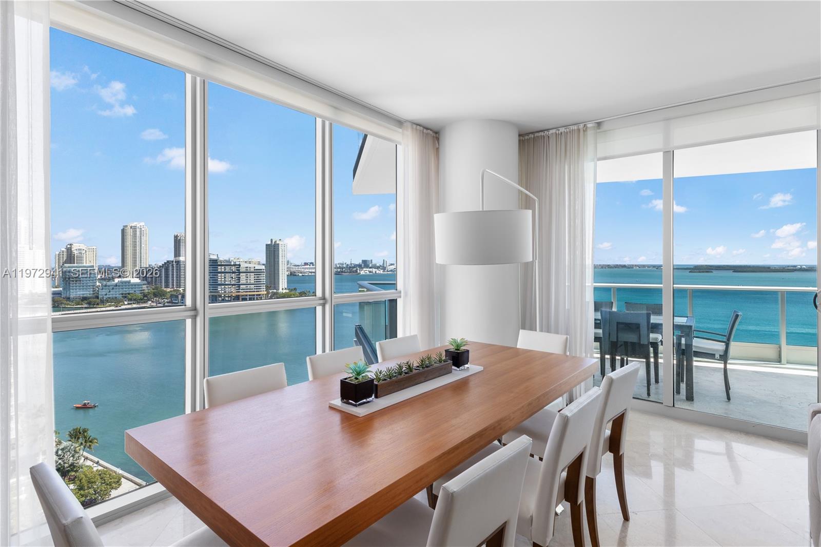 A modern living room features a beige sofa, armchair, and balcony with a water view — 1331 Brickell Bay Dr # 1901, Miami FL 33131, MIAMI, FL