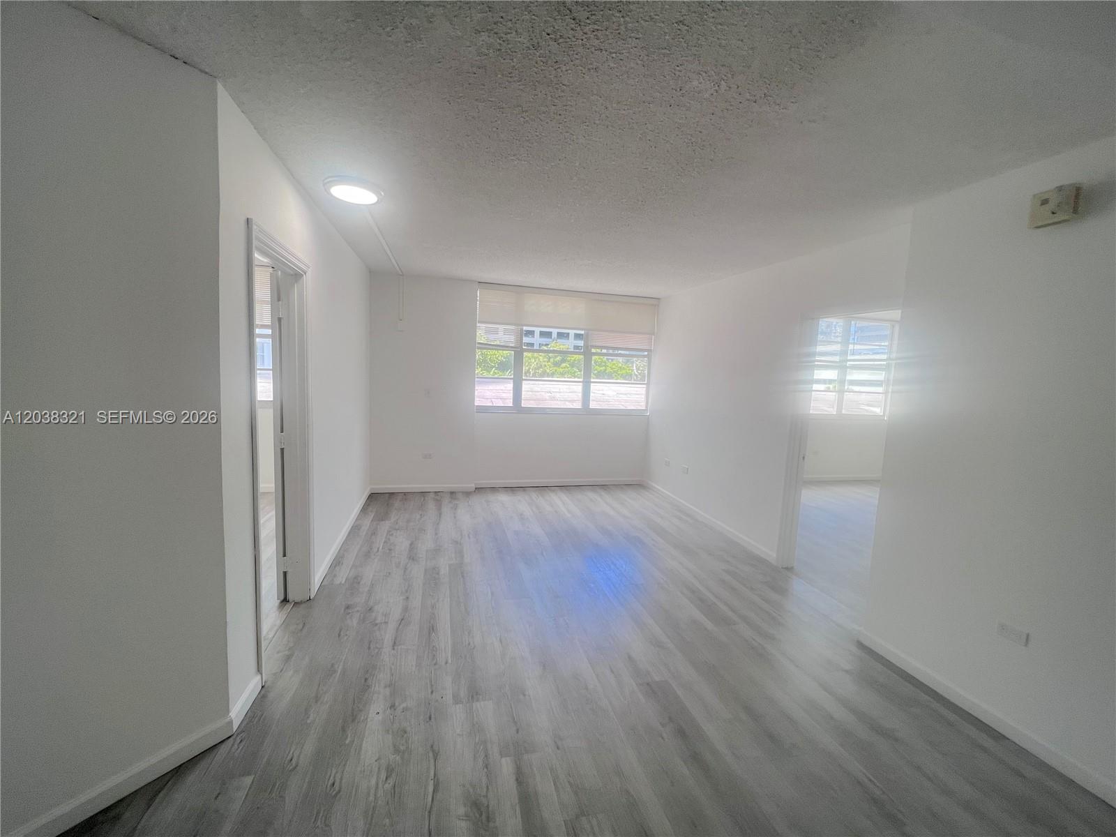 An empty room features white walls, light gray wood-look flooring, and a large window — 801 Brickell Bay Dr # 364, Miami FL 33131, MIAMI, FL