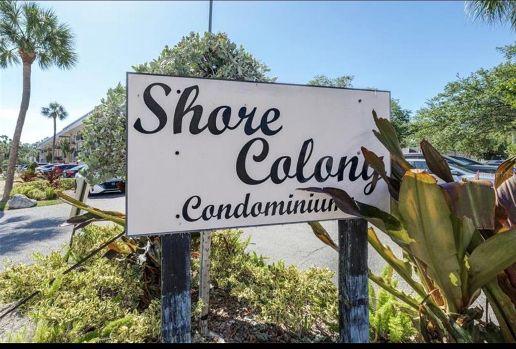 A sign for Shore Colony Condominium stands outdoors near palm trees and a parking lot — 4607 W FIG STREET UNIT 108, TAMPA, FL