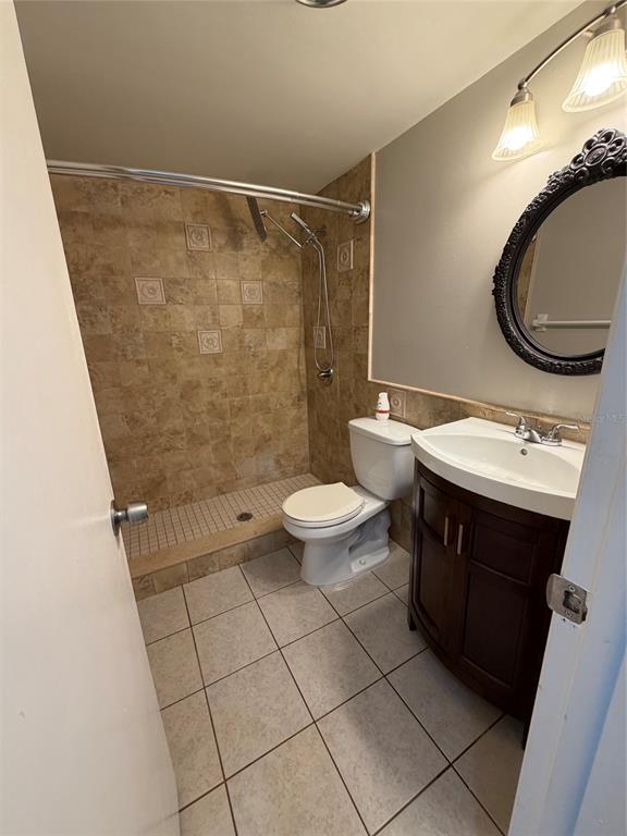 A bathroom features a tiled walk-in shower, a toilet, and a dark wood vanity — 4607 W FIG STREET UNIT 108, TAMPA, FL