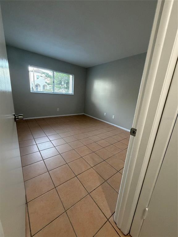 An empty bedroom features light gray walls, a single window, and tan tile flooring — 4607 W FIG STREET UNIT 108, TAMPA, FL