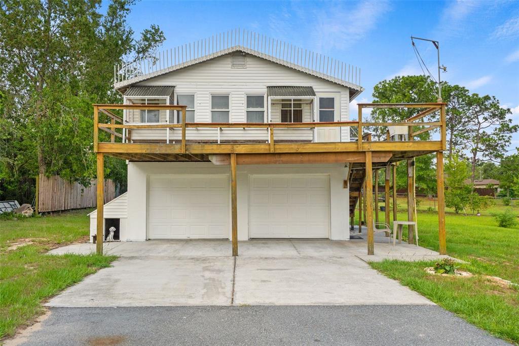 A two-story house features a large wooden deck above a two-car garage — 8020 GRANT STREET, BROOKSVILLE, FL
