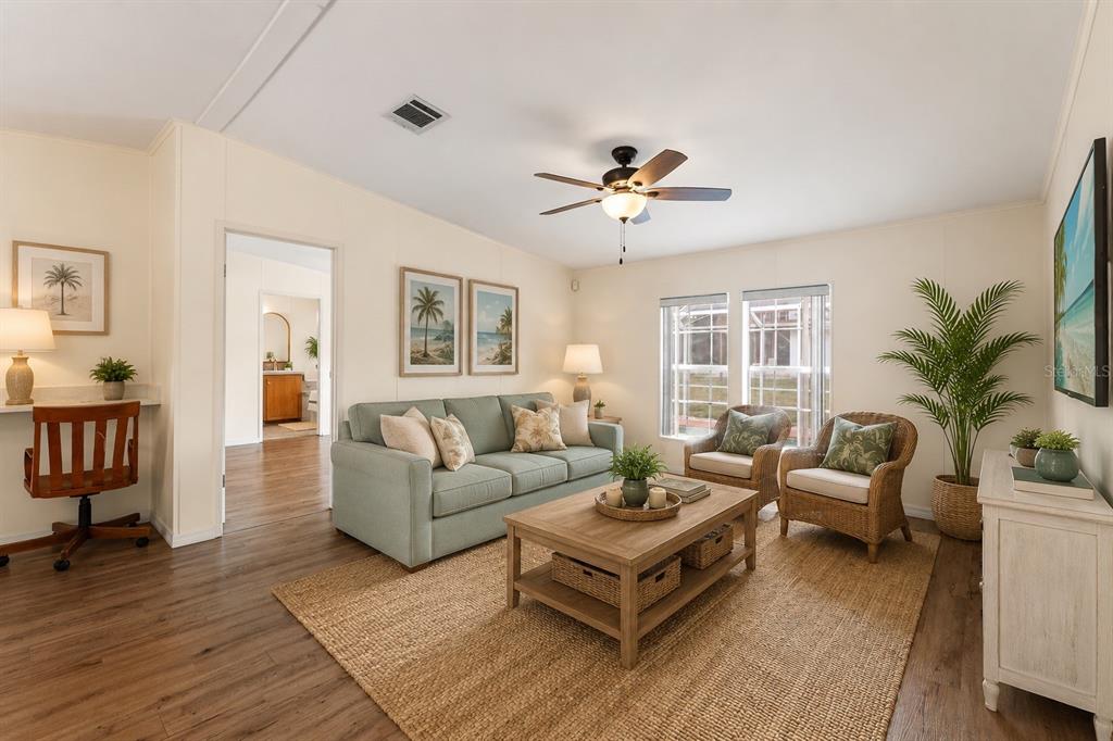A living room features a light green sofa, wicker chairs, a coffee table, and wood flooring — 8020 GRANT STREET, BROOKSVILLE, FL