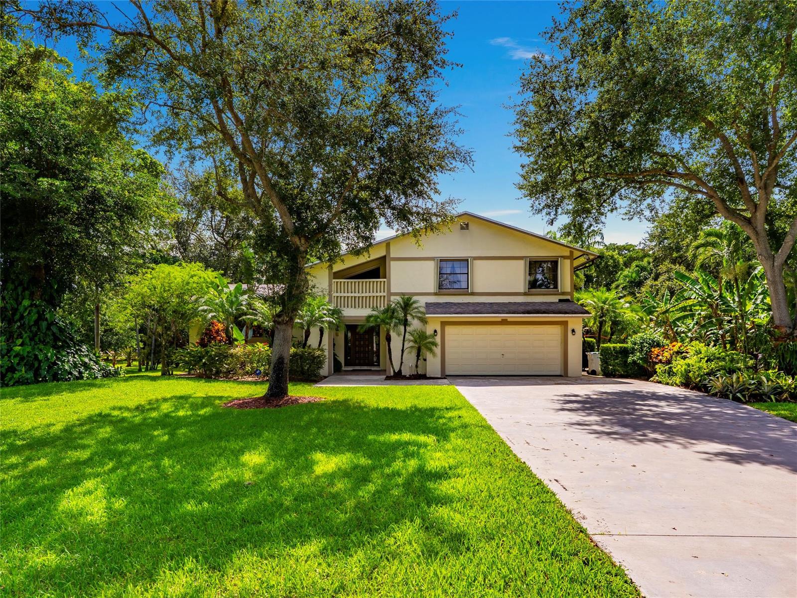A two-story house with a beige exterior, a two-car garage, and a large front lawn — 6556 NW 87th Avenue, Parkland FL 33067, PARKLAND, FL