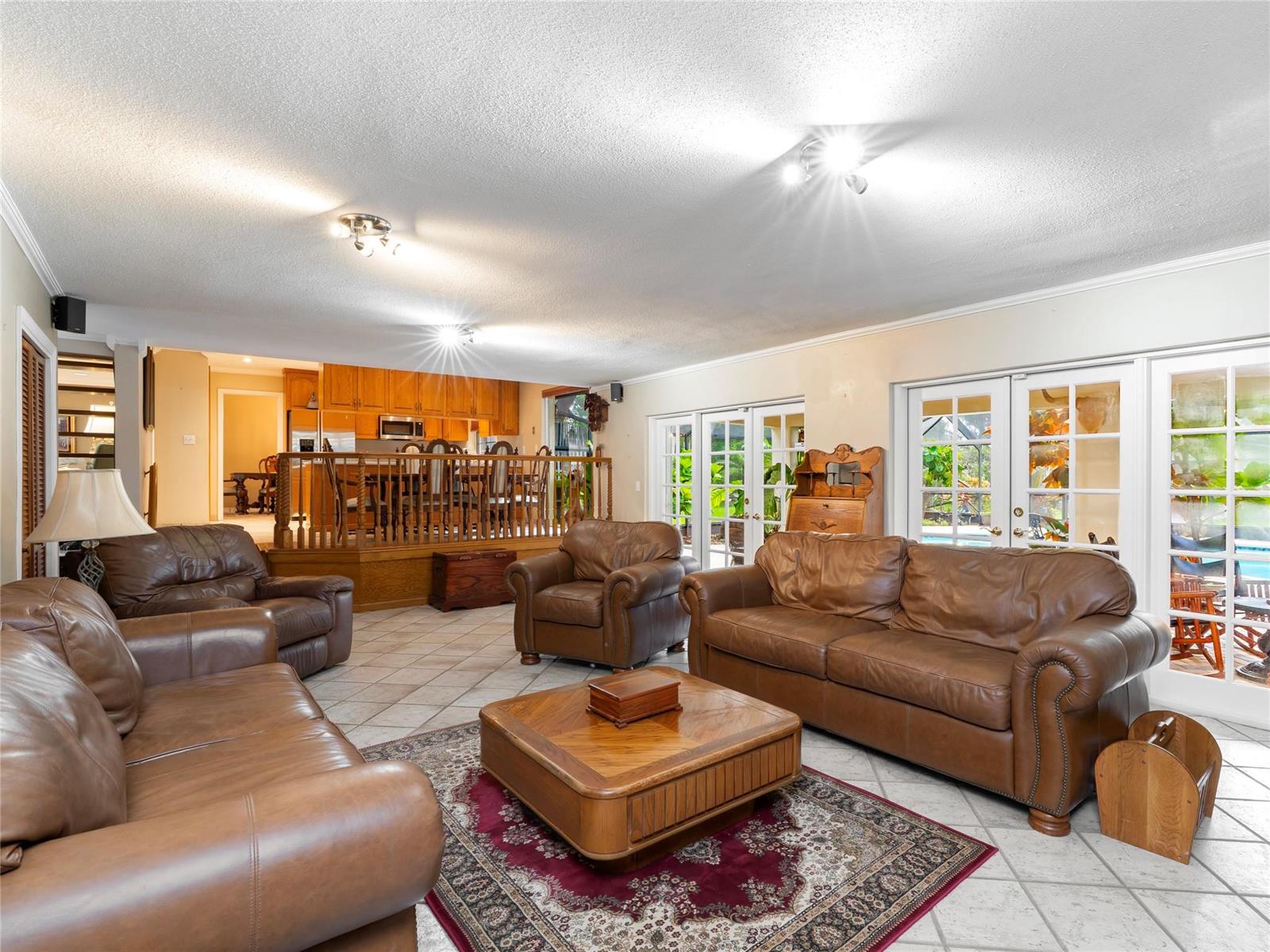 A living room with leather furniture, a wooden coffee table, and a raised dining area — 6556 NW 87th Avenue, Parkland FL 33067, PARKLAND, FL