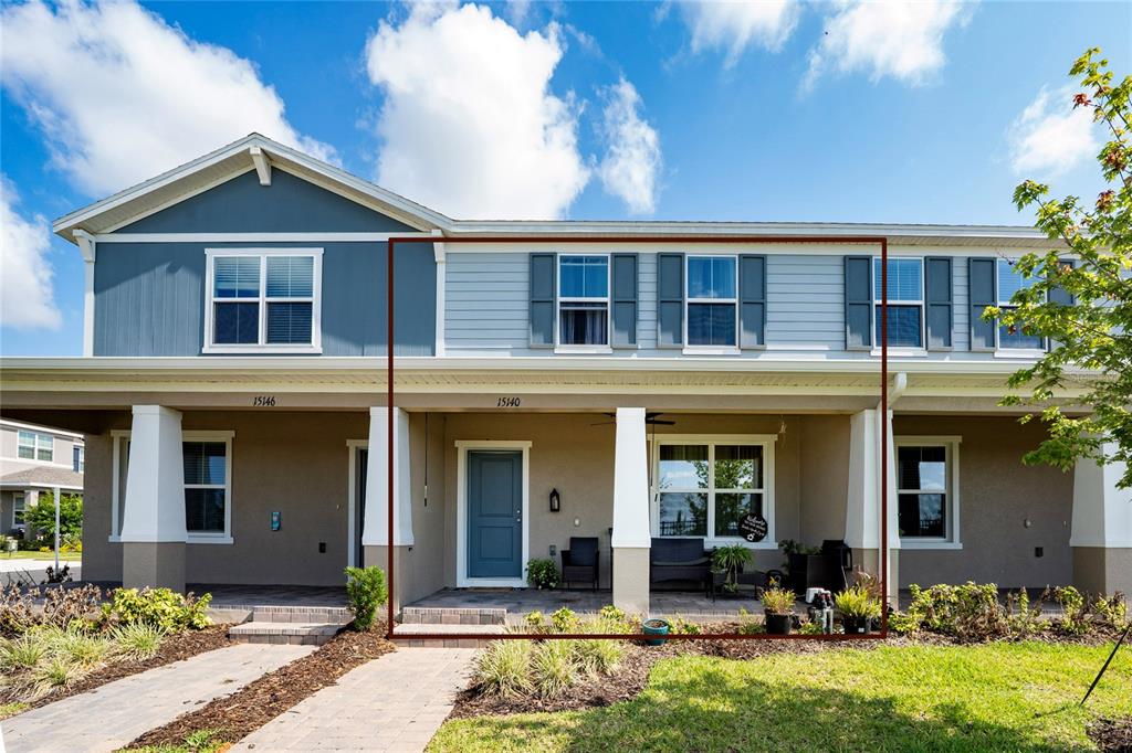 The exterior of a two-story townhouse features blue siding, a covered porch, and white columns — 15140 WINDFLOWER ALLEY, WINTER GARDEN, FL