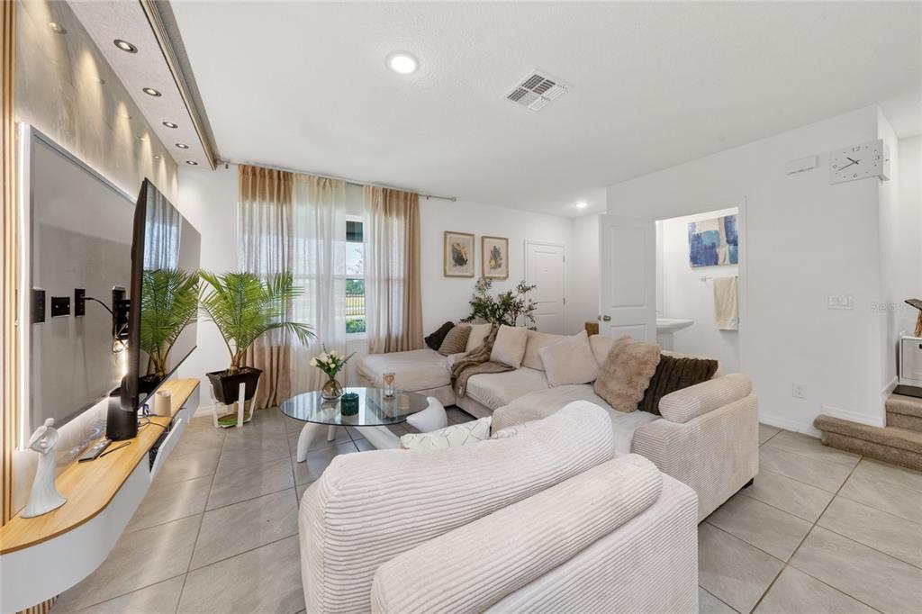A living room features a large sectional sofa, a glass coffee table, and a wall-mounted television — 15140 WINDFLOWER ALLEY, WINTER GARDEN, FL