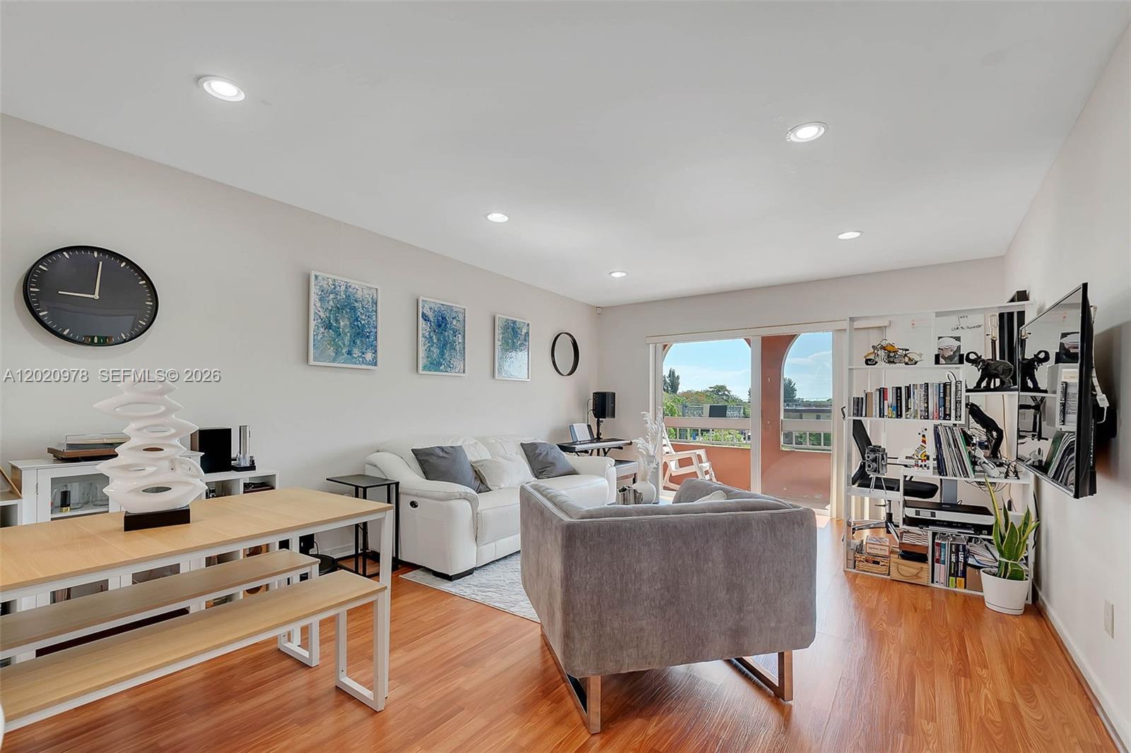 A living room features a white sofa, gray armchair, dining table, and a balcony view — 7701 Camino Real # 416, Miami FL 33143, MIAMI, FL